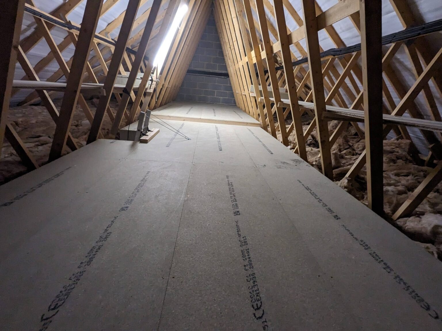 Boarded loft walkway lit by fluorescent strip lighting for safe access