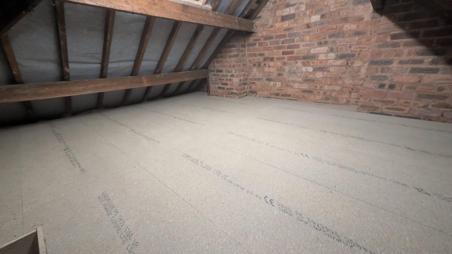 Clean finished loft boarding against original brick gable, Stratford install